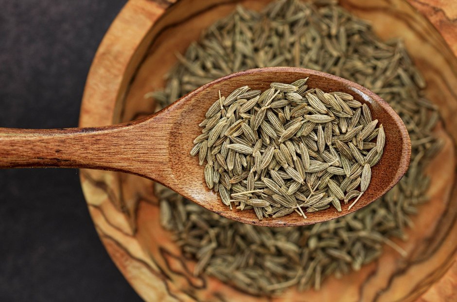 Whole cumin seeds on a wooden spoon