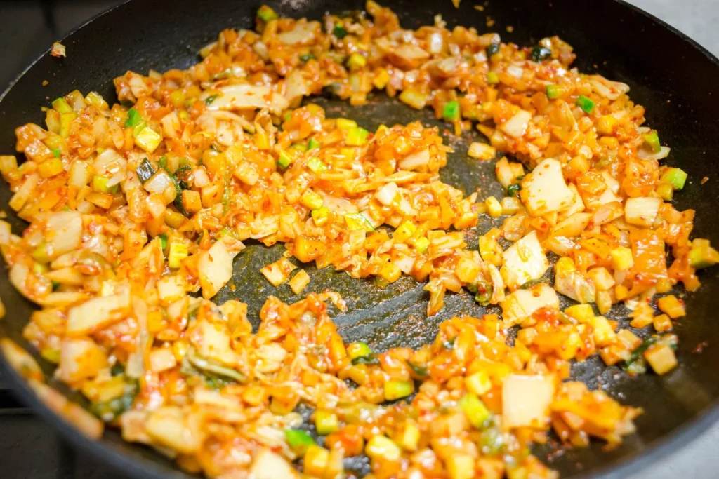 Sautéing carrots, celery, and onions with ground yellow turmeric and ginger in an enameled Dutch oven