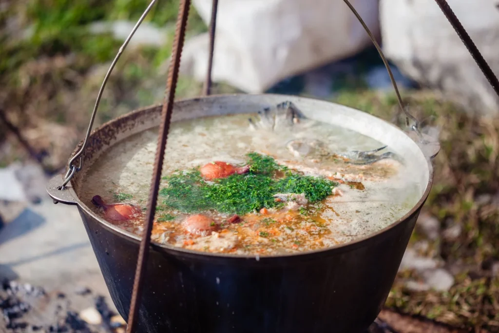 Pouring chicken broth into the sautéed golden aromatics in the pot