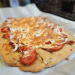 Pre-toasting naan flatbreads on a baking sheet until warm and crisp