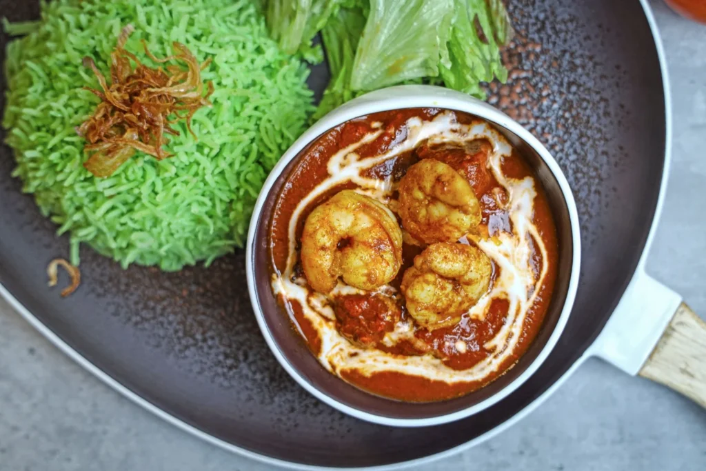 Rich coconut shrimp curry garnished with fresh cilantro served over rice