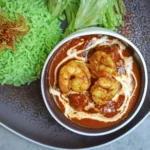 Rich coconut shrimp curry garnished with fresh cilantro served over rice