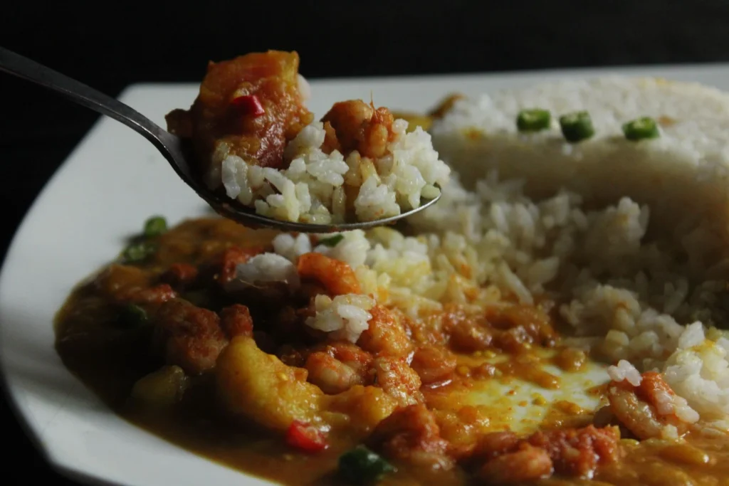Juicy coconut shrimp spooned over steamed rice with fresh lime