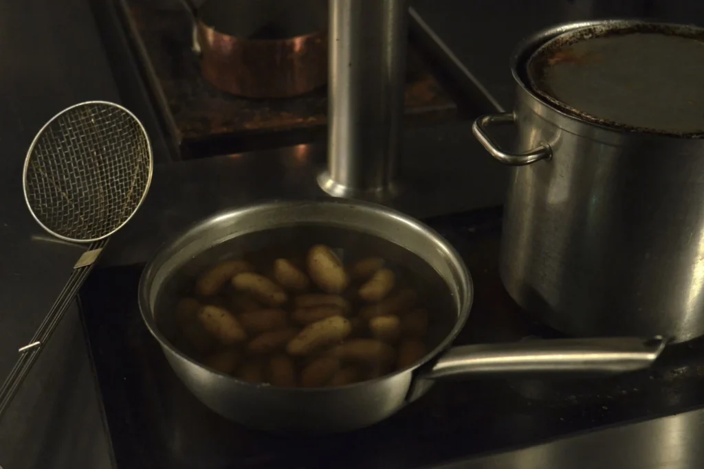 Boiling whole baby Yukon gold potatoes until tender in a pot