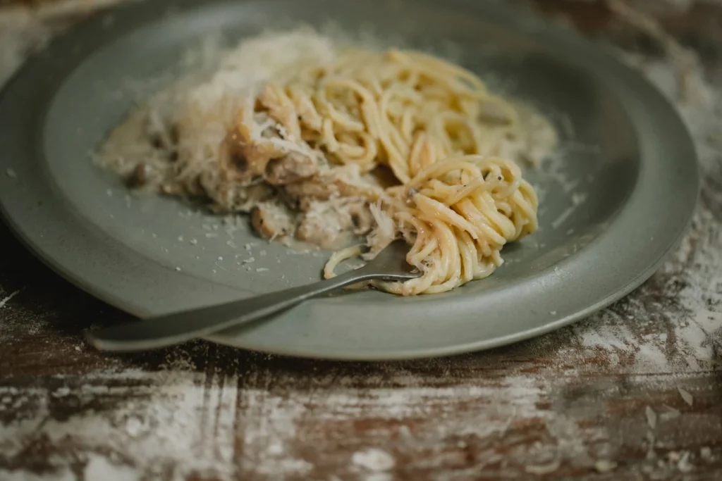 Fork twirling creamy butter chicken pasta garnished with parmesan
