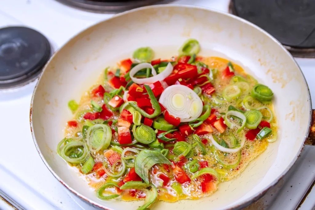 Stir-frying sliced bell peppers and onions over high heat in a skillet